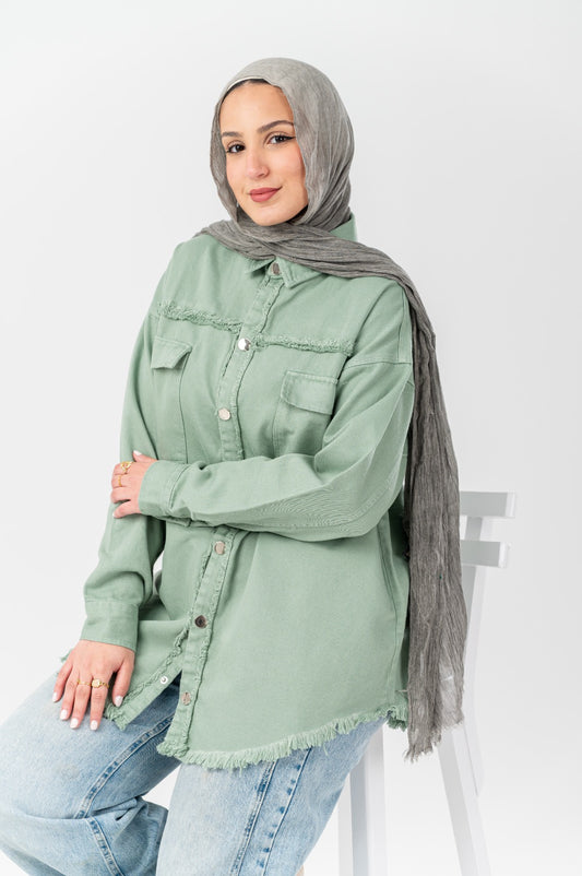 Akira distressed denim shirt featuring a casual fit and distressed details, shown on a model with rolled sleeves and front pockets.