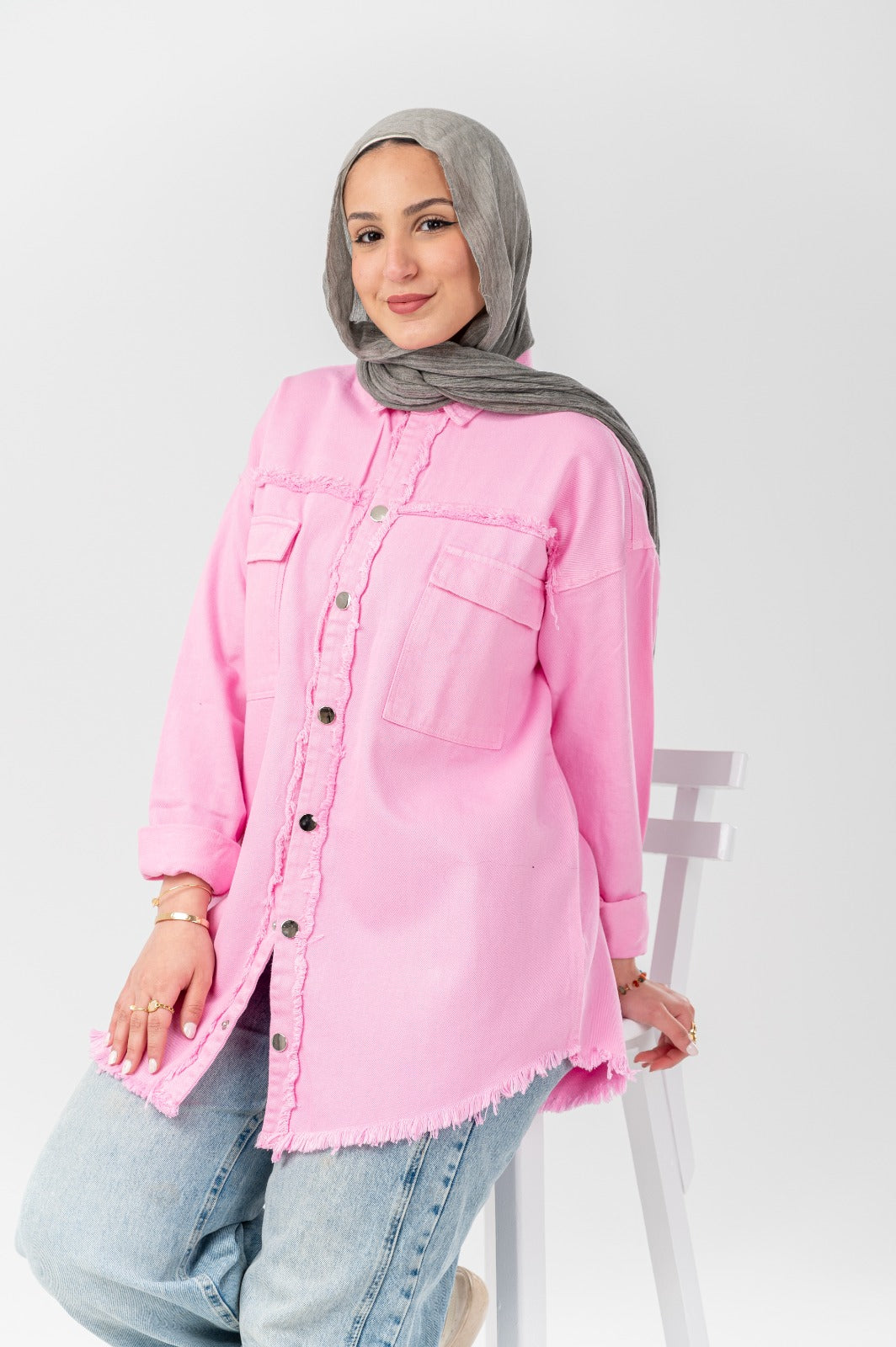 Akira distressed denim shirt with frayed edges and worn look, displayed on a hanger against a neutral background.