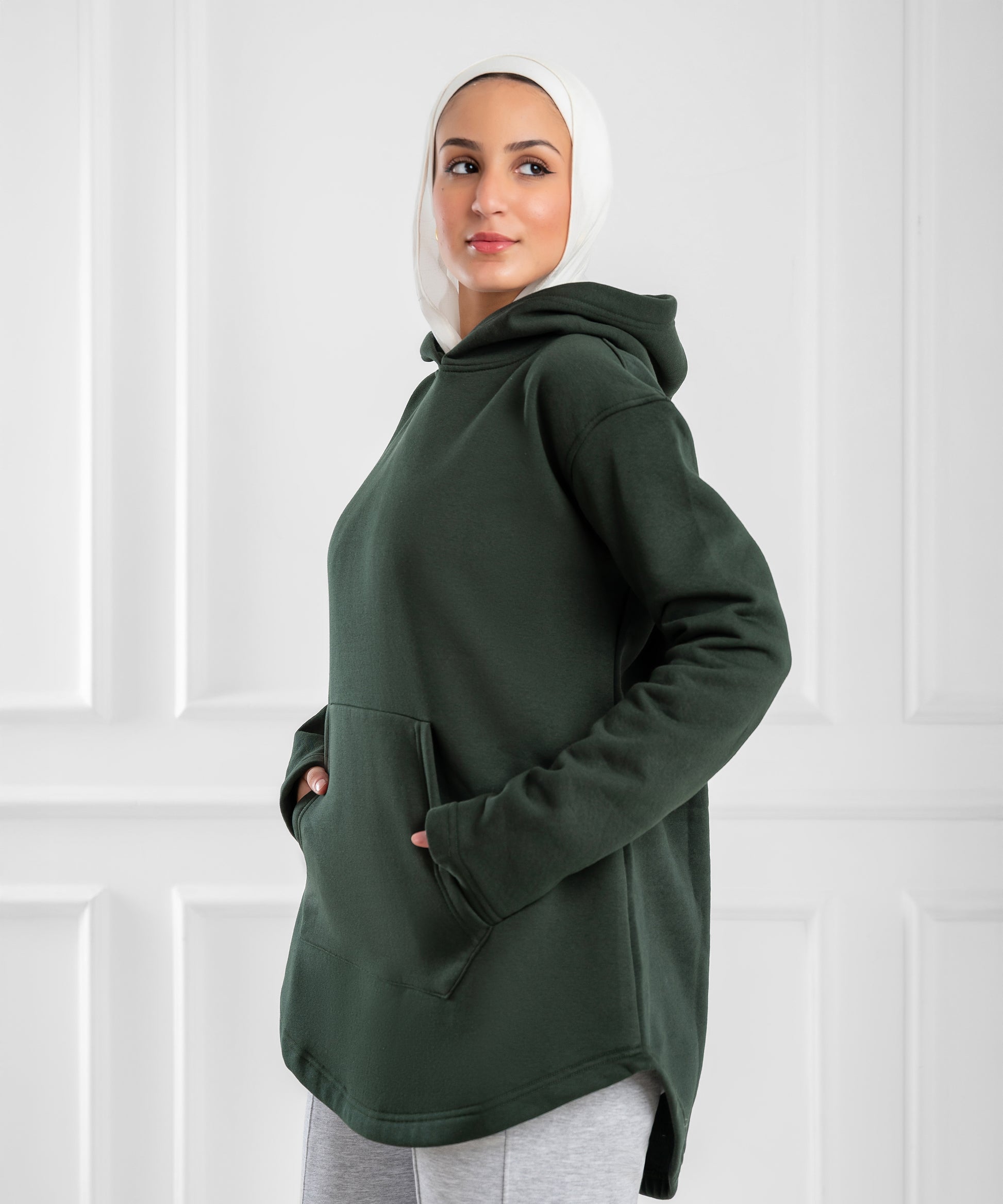 Akira curved-hem fleece tunic hoodie hanging on a rack, showing soft fabric, relaxed fit, and stylish curved hem design.