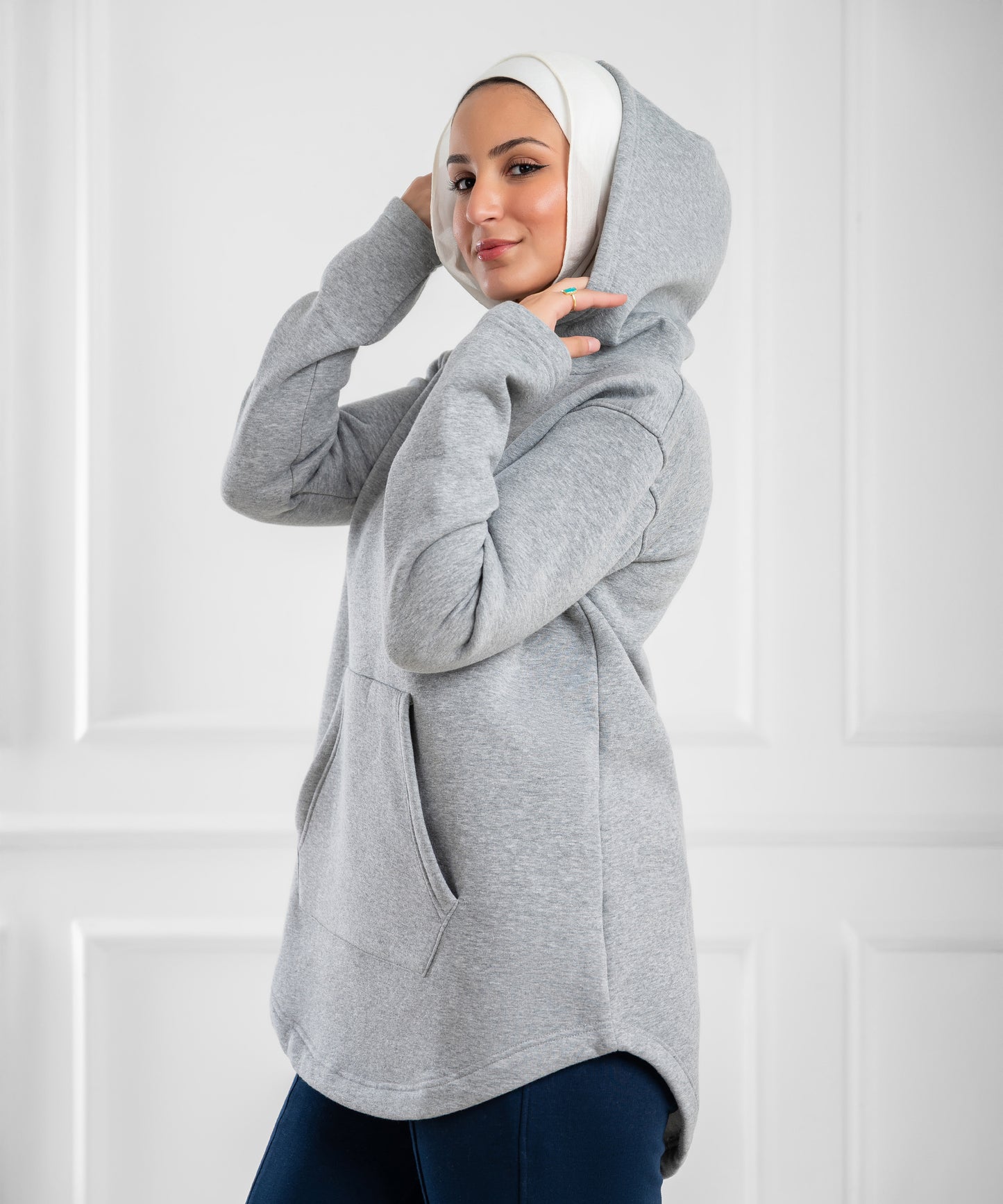Akira curved-hem fleece tunic hoodie displayed on model, showing soft fabric, relaxed fit, and stylish curved hem design.