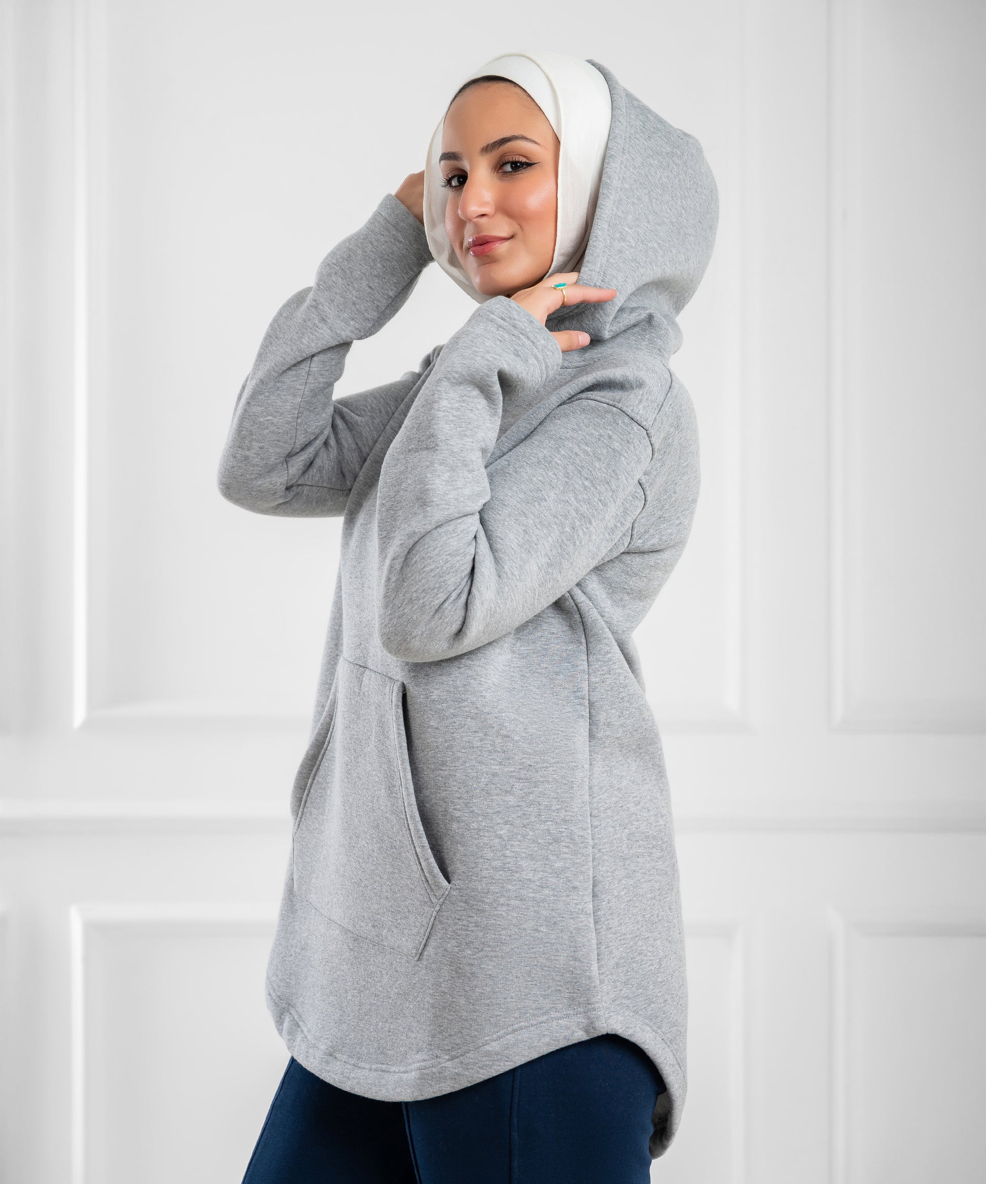 Akira curved-hem fleece tunic hoodie displayed on model, showing soft fabric, relaxed fit, and stylish curved hem design.