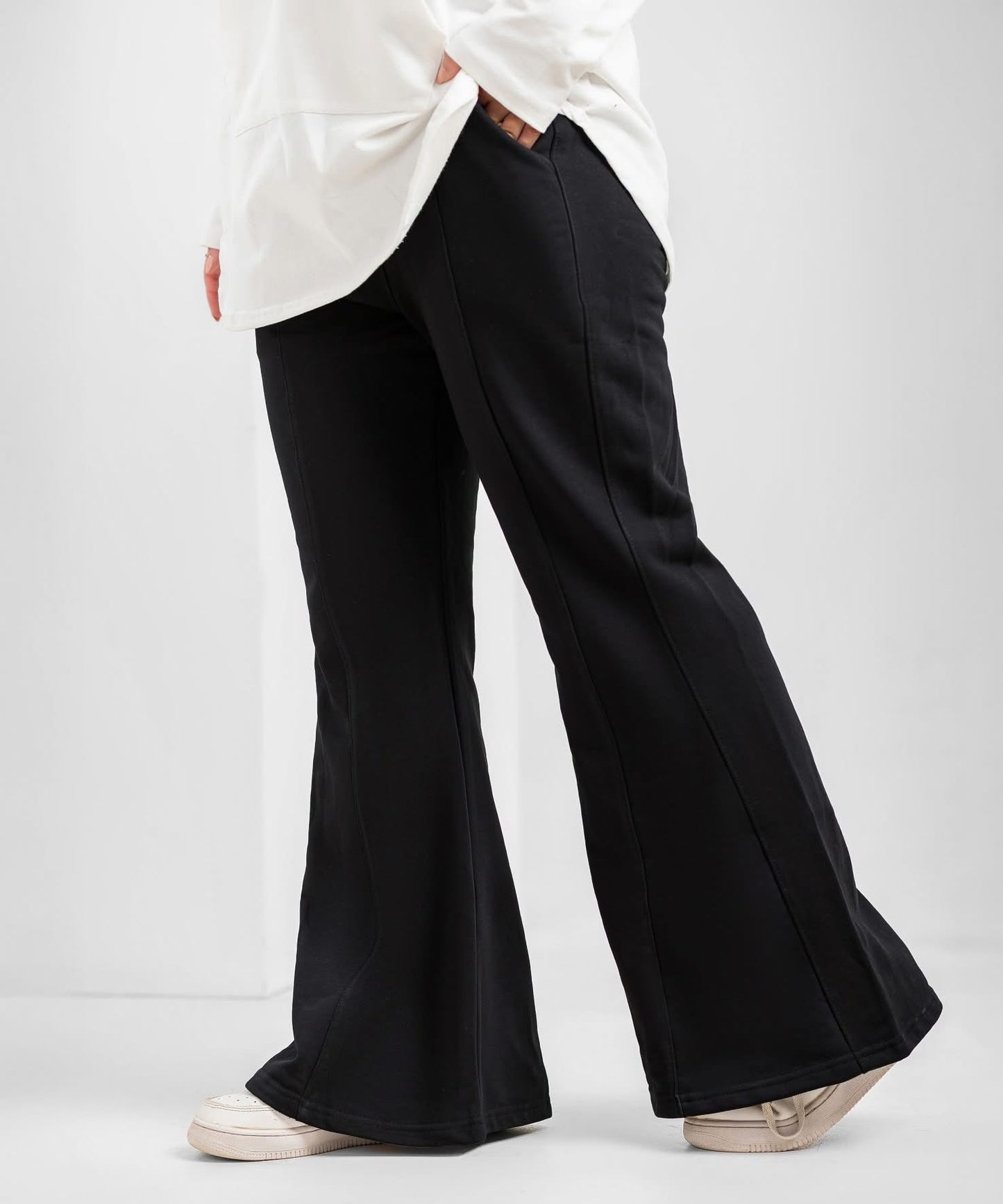 Black flare pants by Akira displayed on a model, featuring high-waisted fit and wide-leg silhouette for a stylish, casual look.
