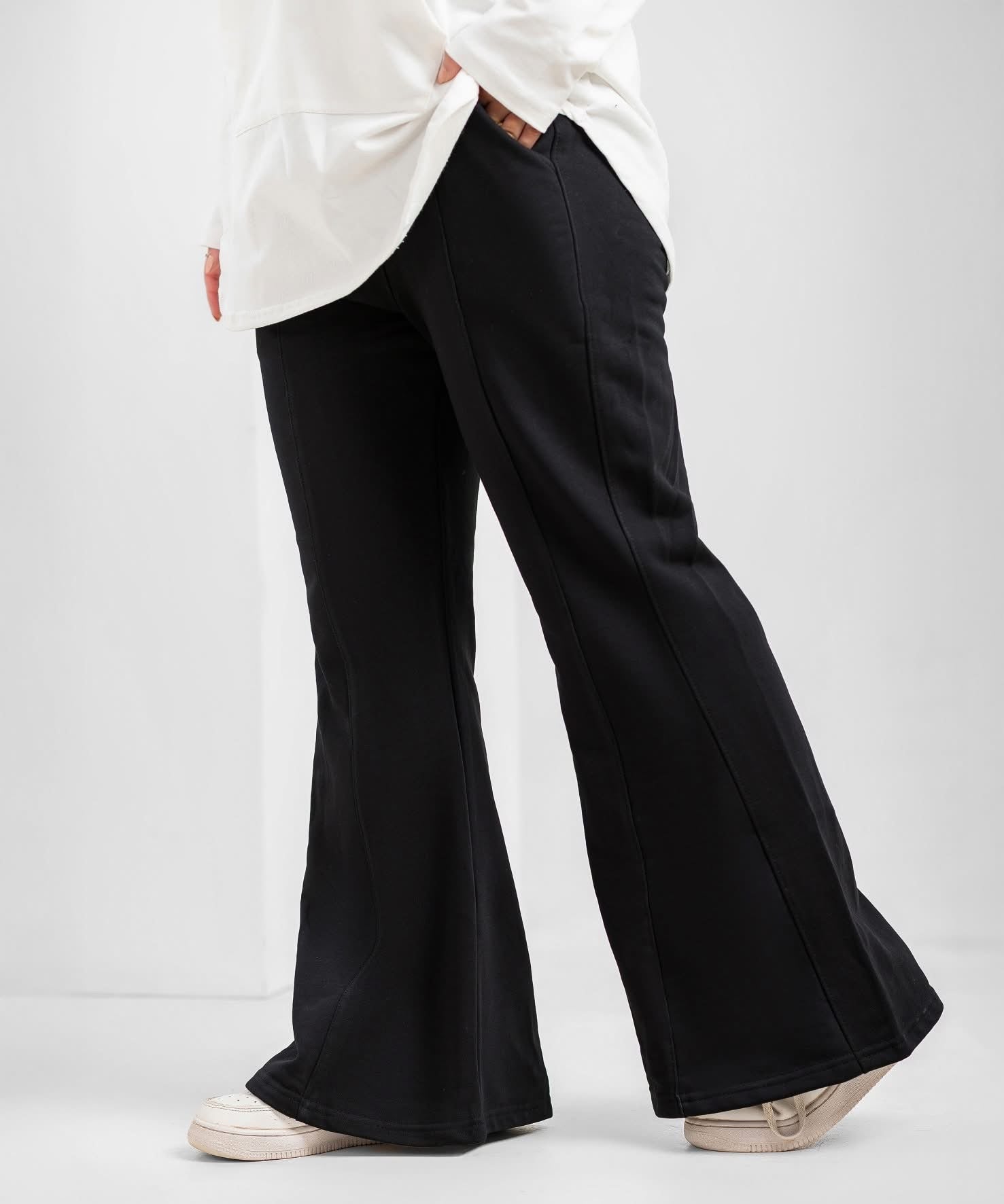 Black flare pants by Akira displayed on a model, featuring high-waisted fit and wide-leg silhouette for a stylish, casual look.