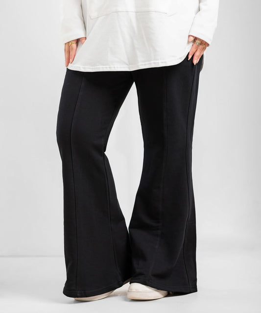 Black flare pants from Akira, showcasing their high-waisted fit and wide-leg design on a model.