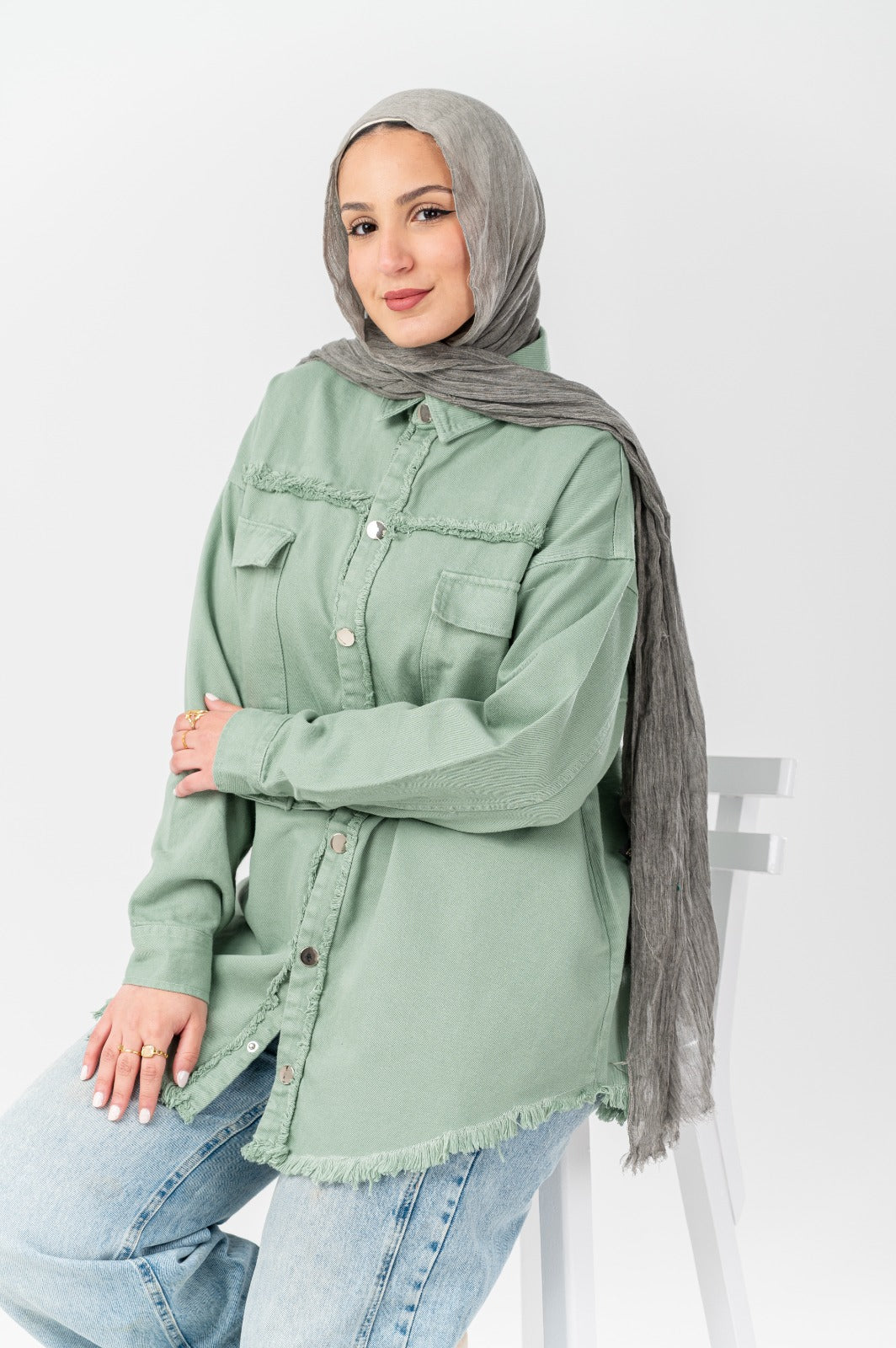 Akira distressed denim shirt featuring a casual fit and distressed details, shown on a model with rolled sleeves and front pockets.